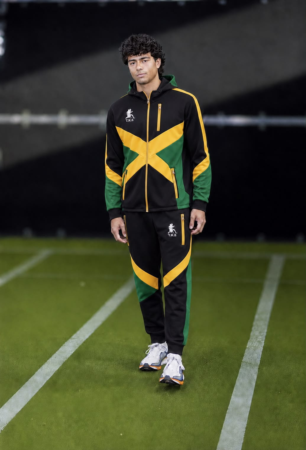 Model wearing the TKE black, green, and gold matching hooded jumpsuit with zip-front jacket and pants.